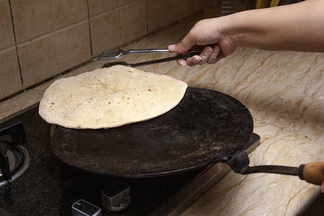 person holding stainless steel fork, Cooking an Asian Bread on heat cooker