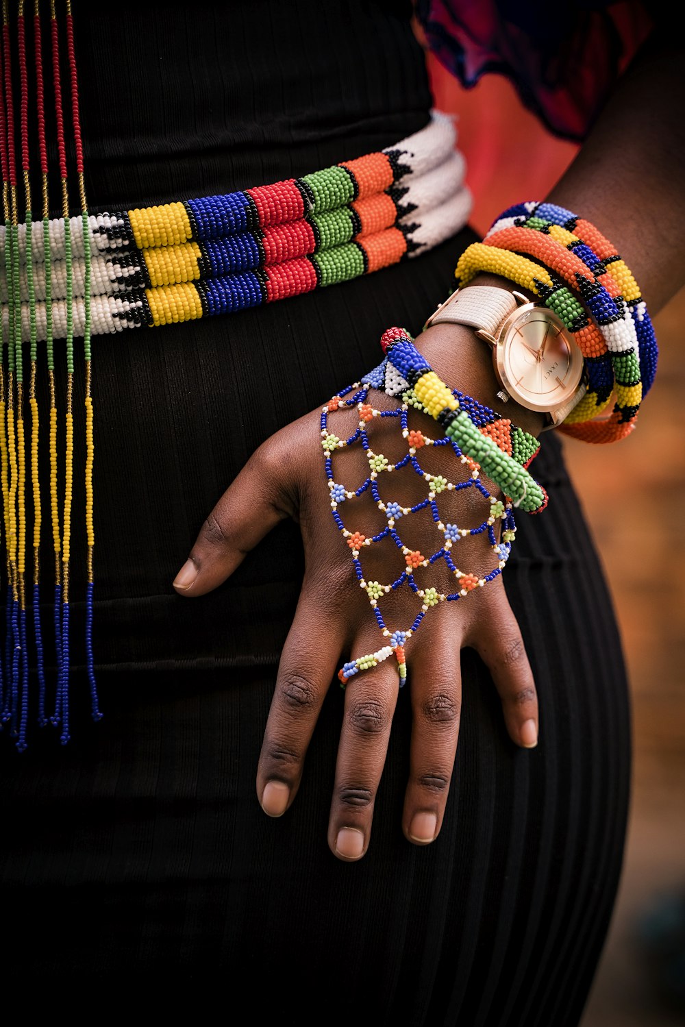 person holding beaded blue and yellow necklace