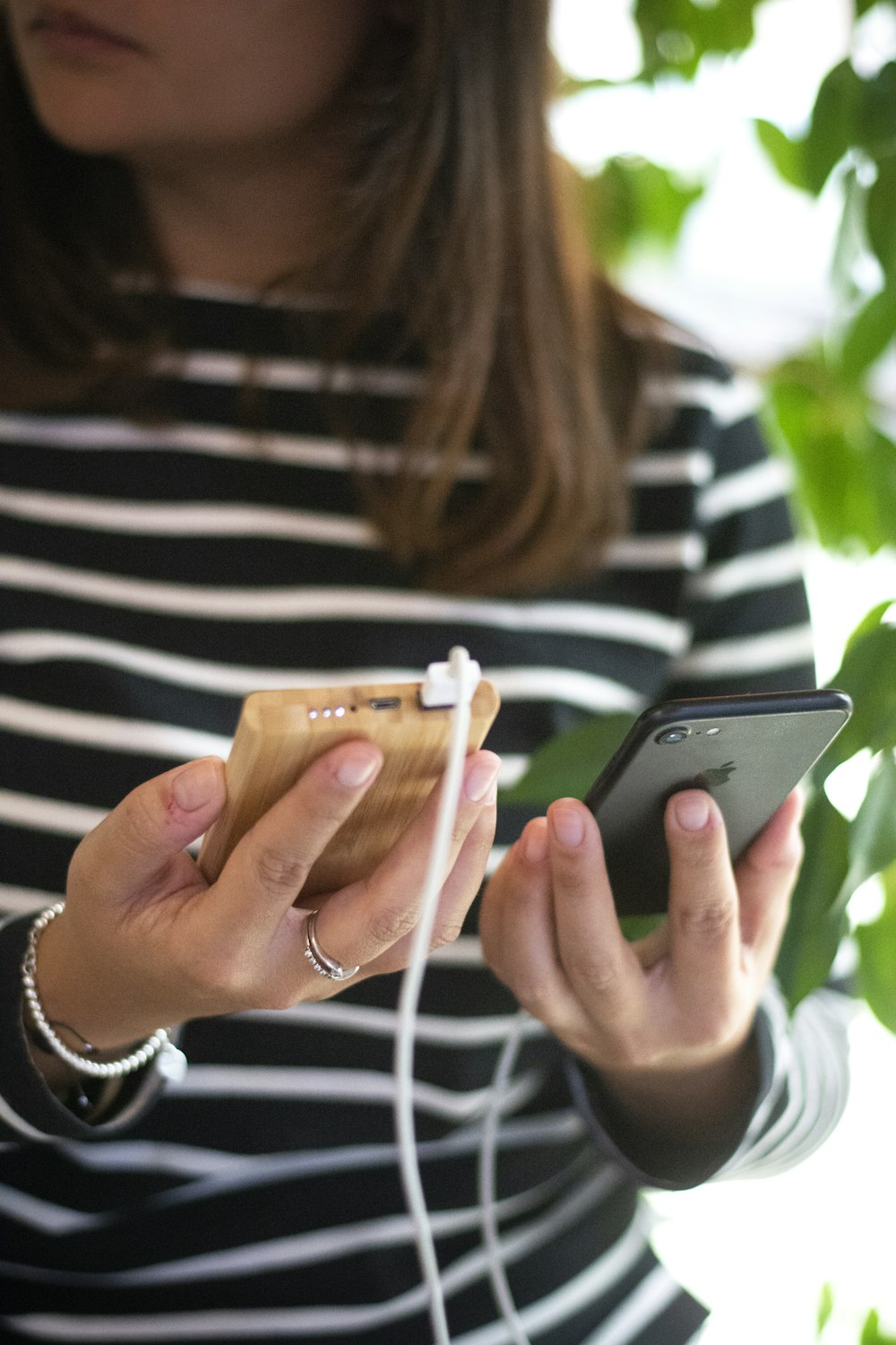 mulher na camisa de manga longa listrada preta e branca segurando iphone prata 6