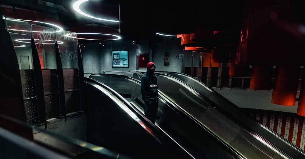 man in black jacket walking on the escalator