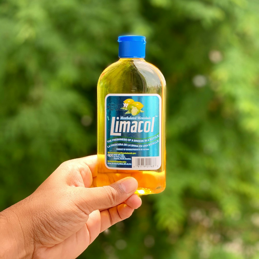 person holding yellow and blue plastic bottle