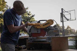 man in blue t-shirt and brown hat holding yellow and black excavator