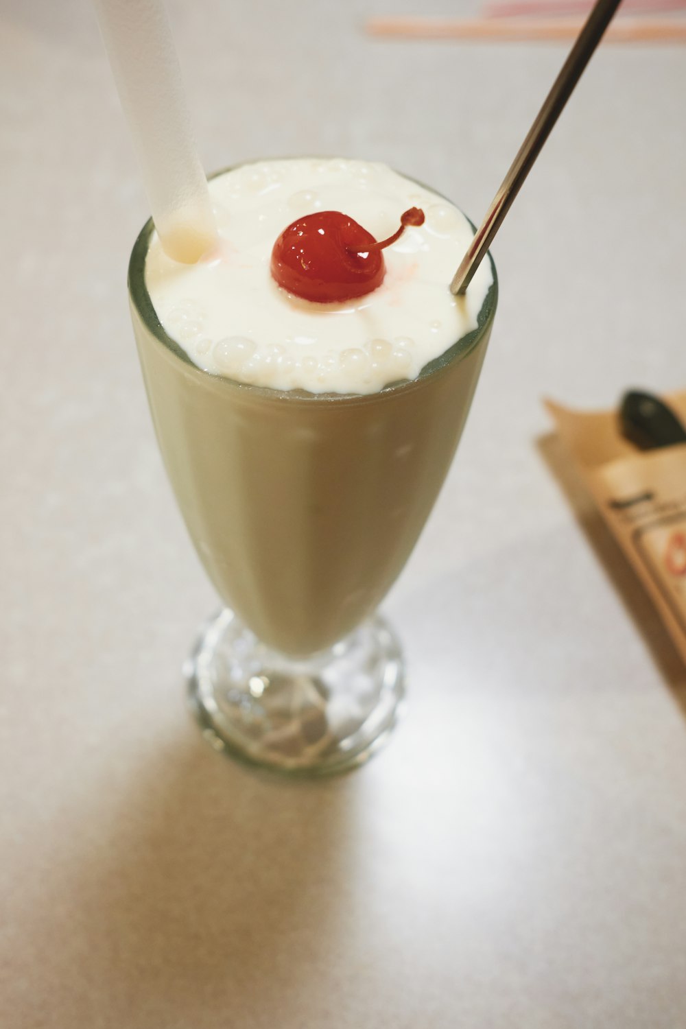 clear drinking glass with white liquid and cherry on top