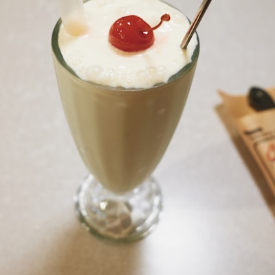 clear drinking glass with white liquid and cherry on top