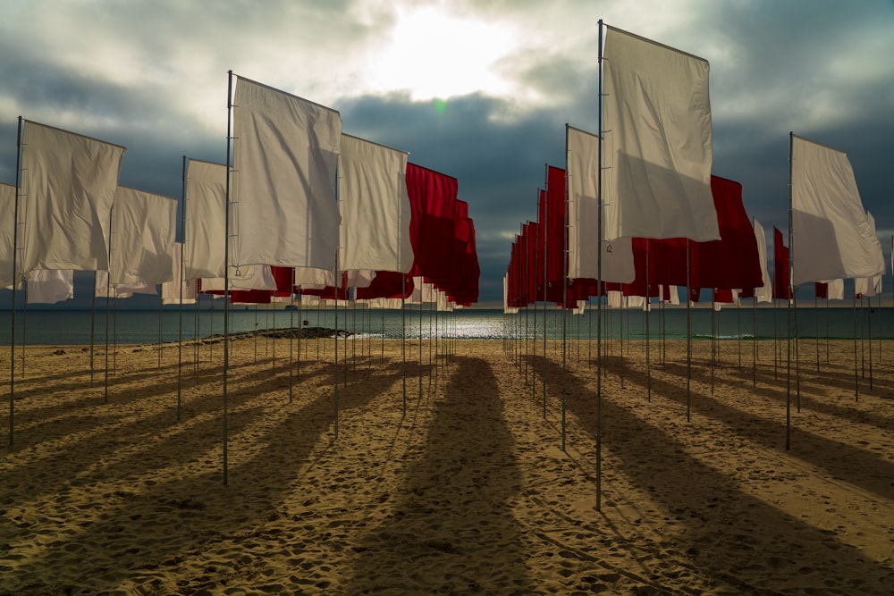 drapeaux blancs, rouges et bleus sur le sable brun sous les nuages blancs pendant la journée