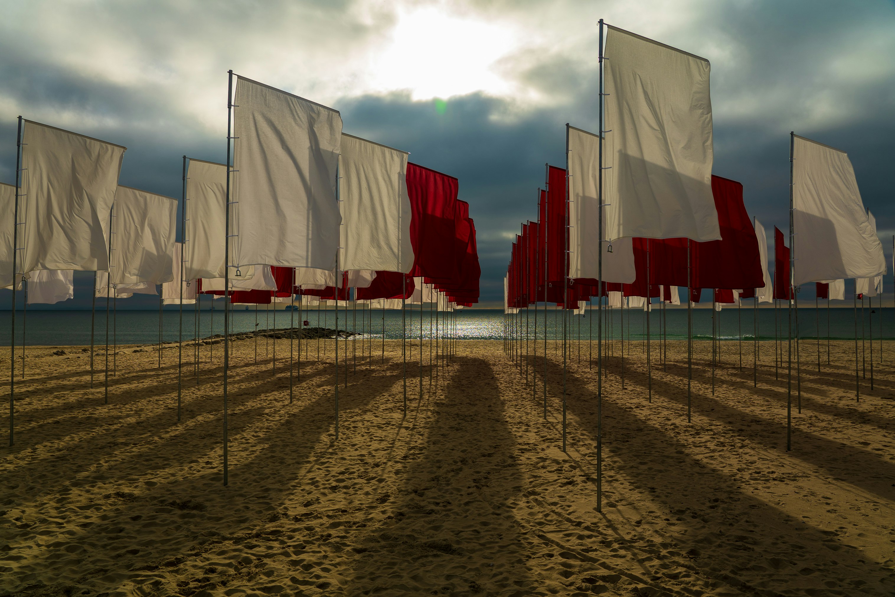 white red and blue flags on brown sand under white clouds during daytime