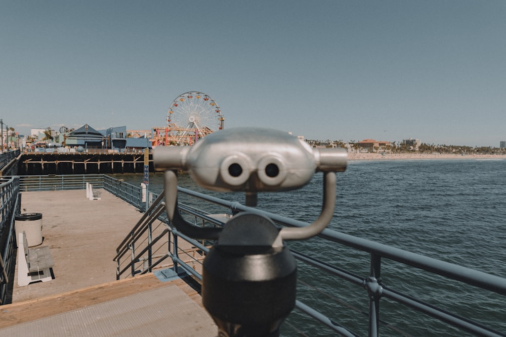 black and silver telescope near body of water during daytime