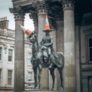 statue of man riding horse near white concrete building during daytime
