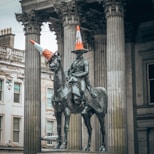 statue of man riding horse near white concrete building during daytime