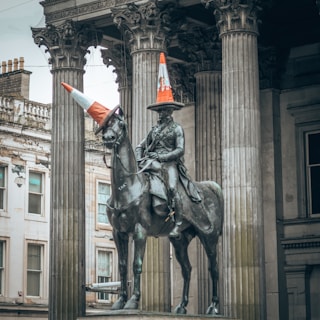 statue of man riding horse near white concrete building during daytime