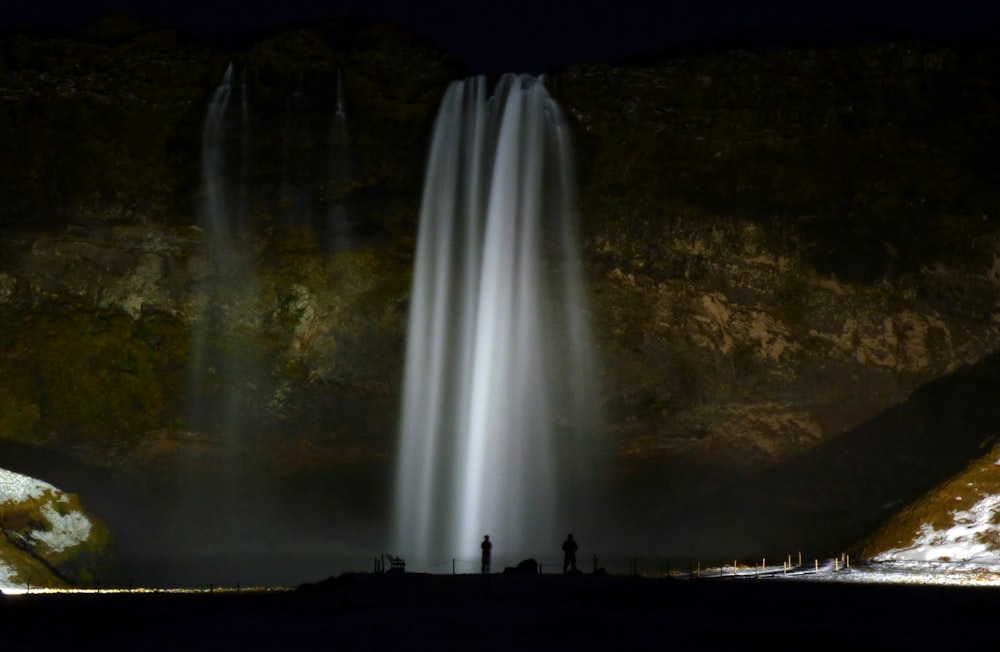 silhouette of people standing near waterfalls during daytime