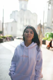 A lifestyle shot of a young woman in a cozy hoodie, walking confidently through an urban street with muted tones.