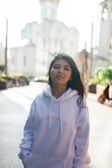 Model wearing a cozy jersey hoodie walking through a sunlit urban street.