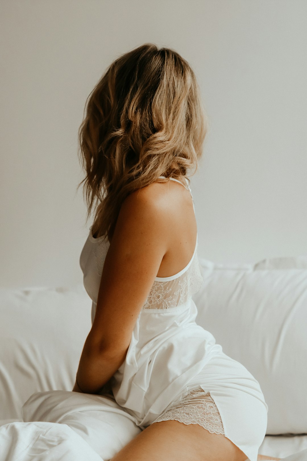 woman in white dress lying on bed