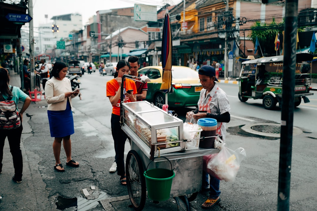 people in a street with cars parked on the side during daytime