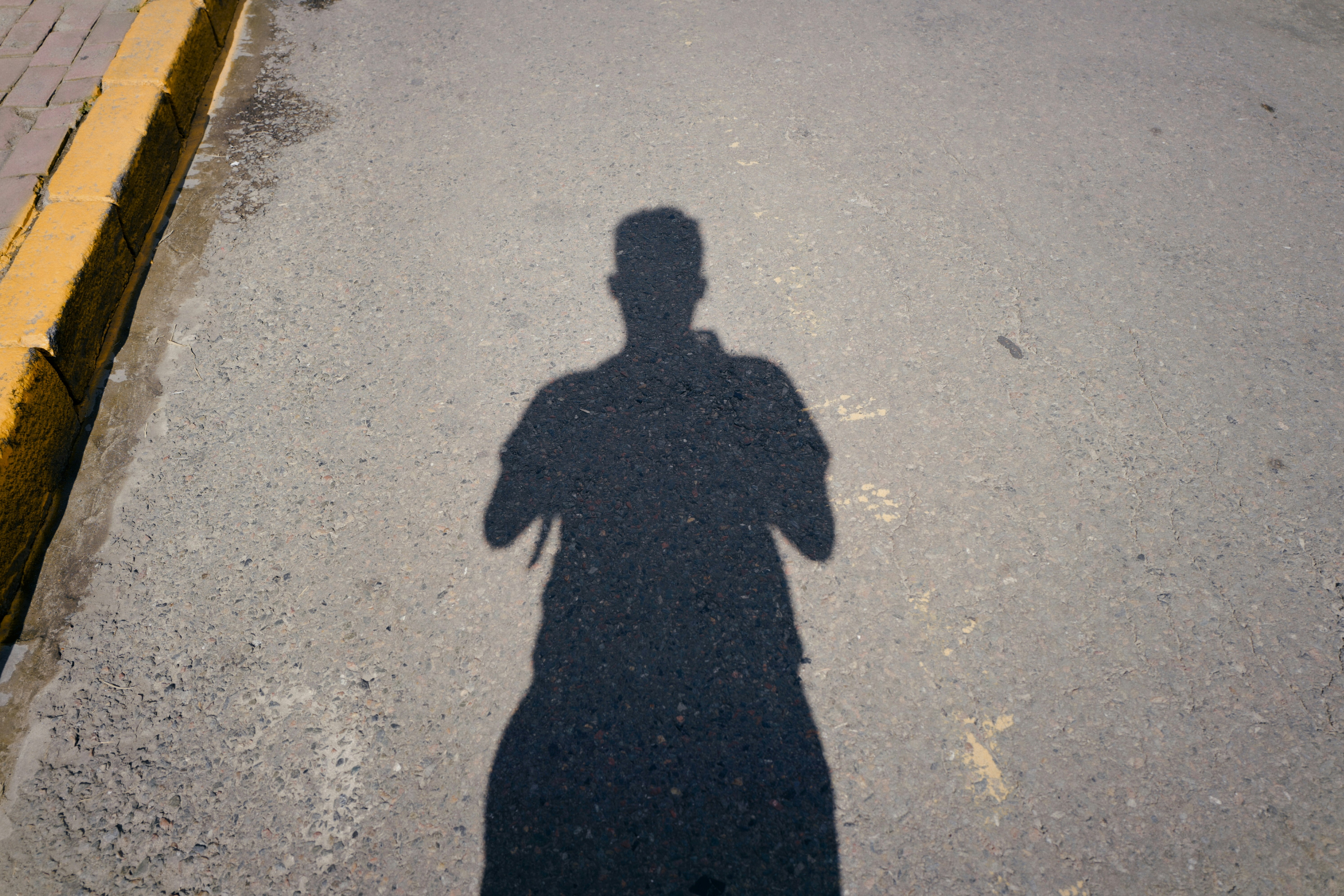 shadow of person on gray concrete road during daytime