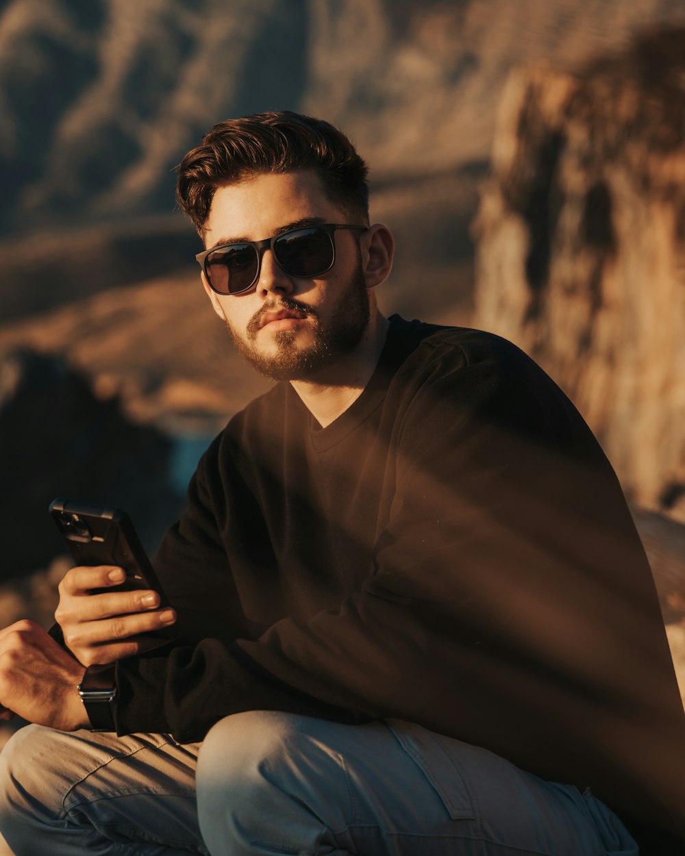 man in black long sleeve shirt holding black smartphone