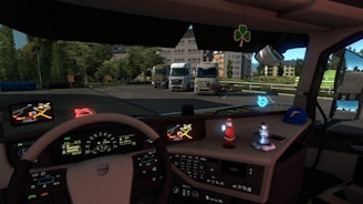 Inside the cabin of a truck, a detailed dashboard is visible with multiple controls and screens displaying maps and vehicle information. Ornamental figures, including a Santa Claus figure and a winter-themed character, are placed on the dashboard along with a cap. Outside the cabin, several parked trucks and greenery are visible, indicating a truck parking or rest area.