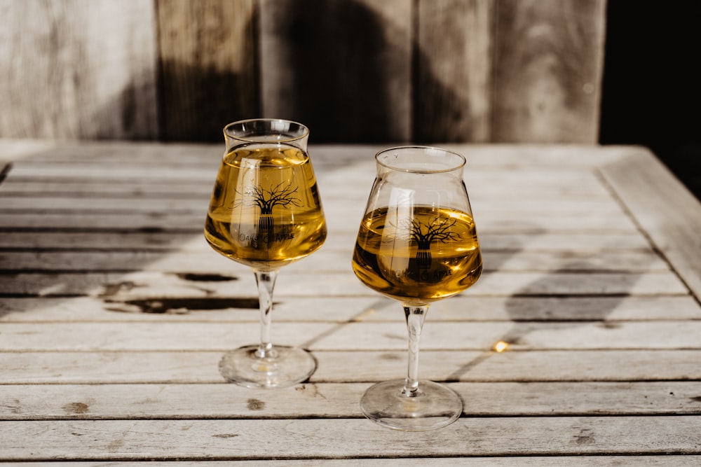 two clear wine glasses on brown wooden table