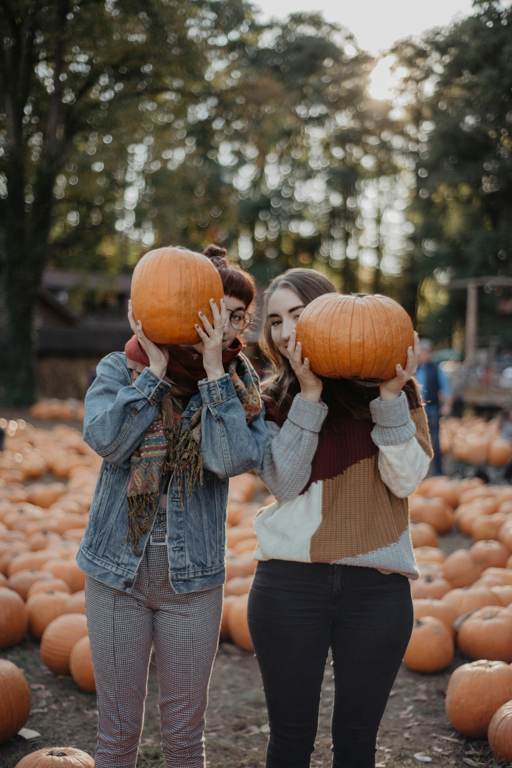 Donna in giacca di jeans blu che tiene la zucca durante il giorno