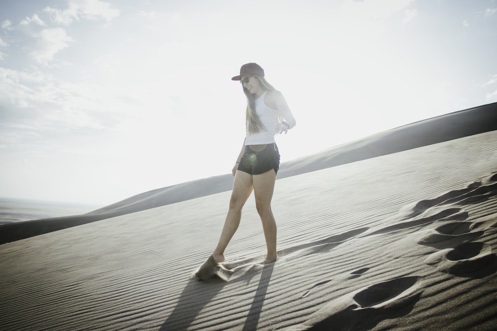 woman in white shirt and blue shorts standing on beach during daytime