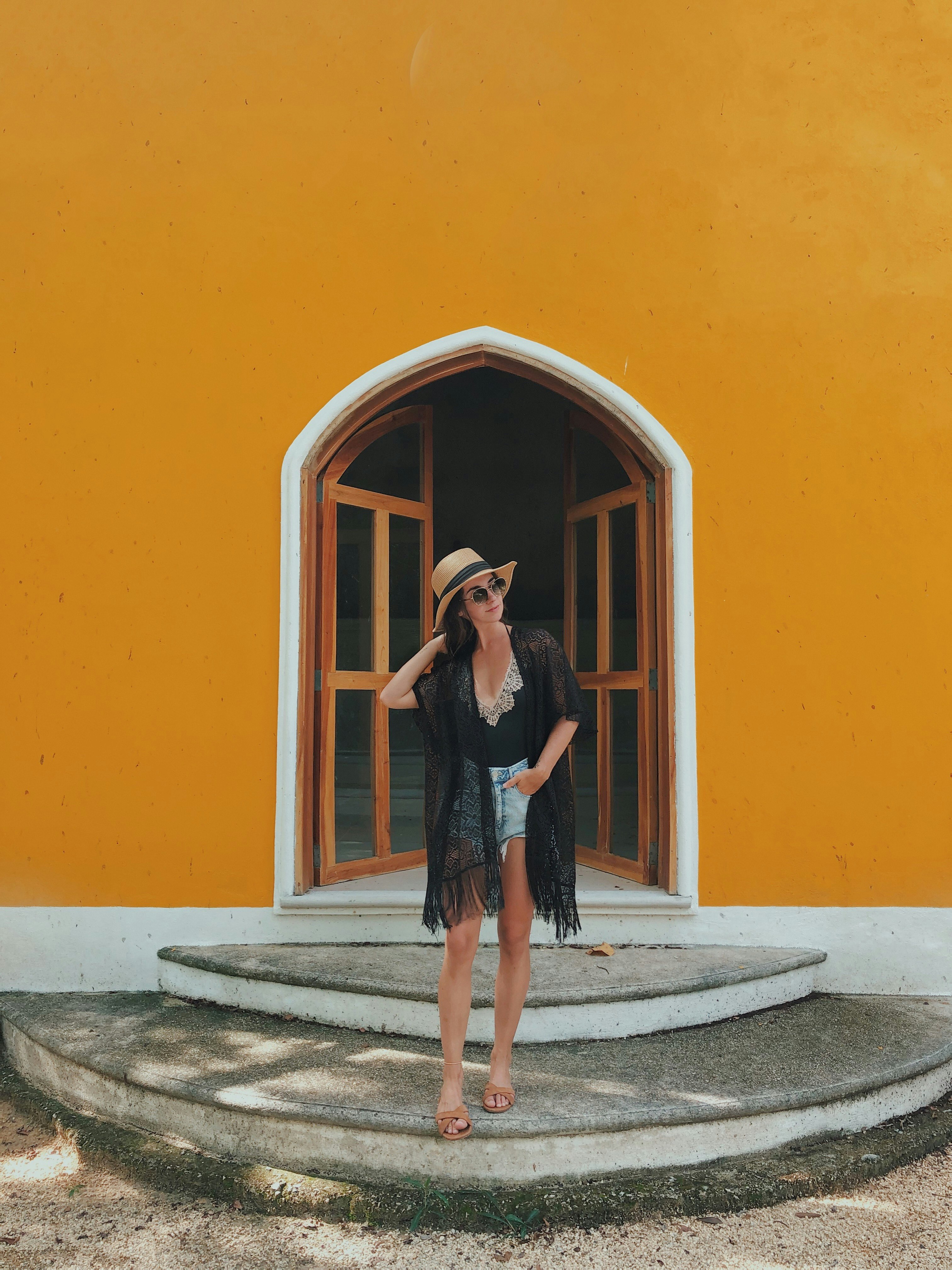woman in black dress standing beside orange wall