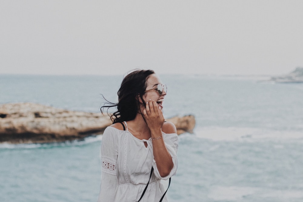 woman in white crew neck t-shirt covering her face with her hand