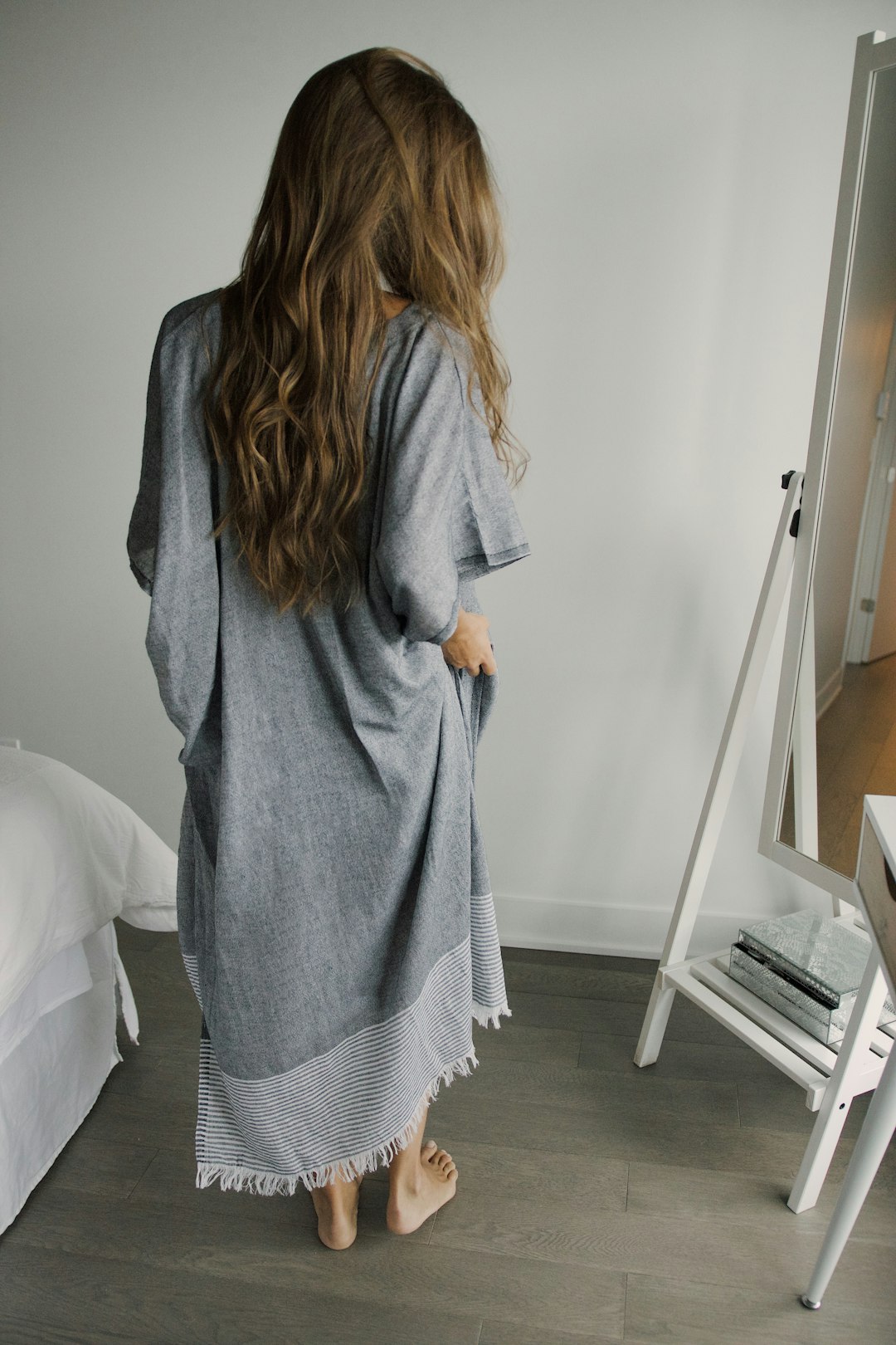 woman in gray sweater standing beside white wall