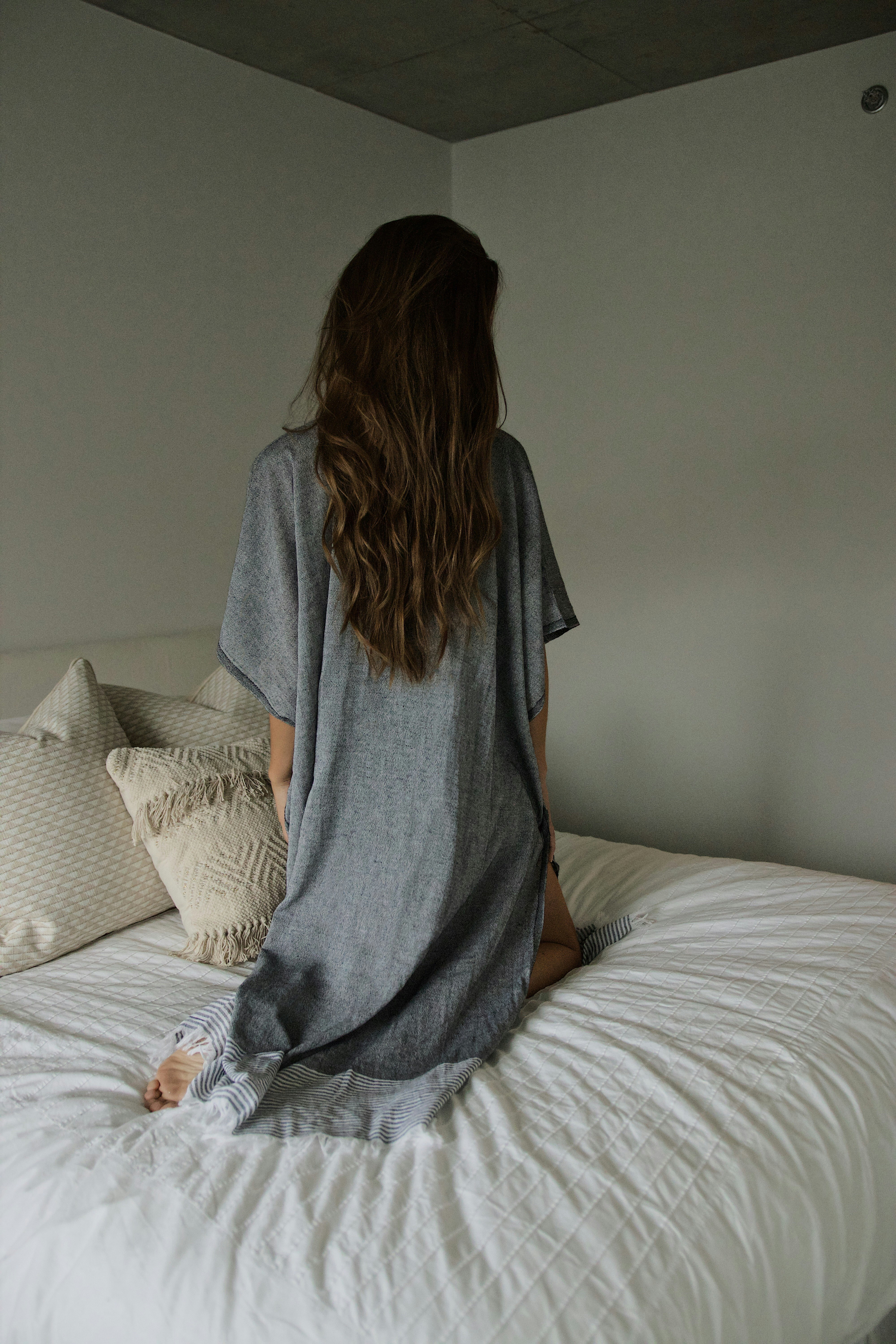 woman in gray robe sitting on bed