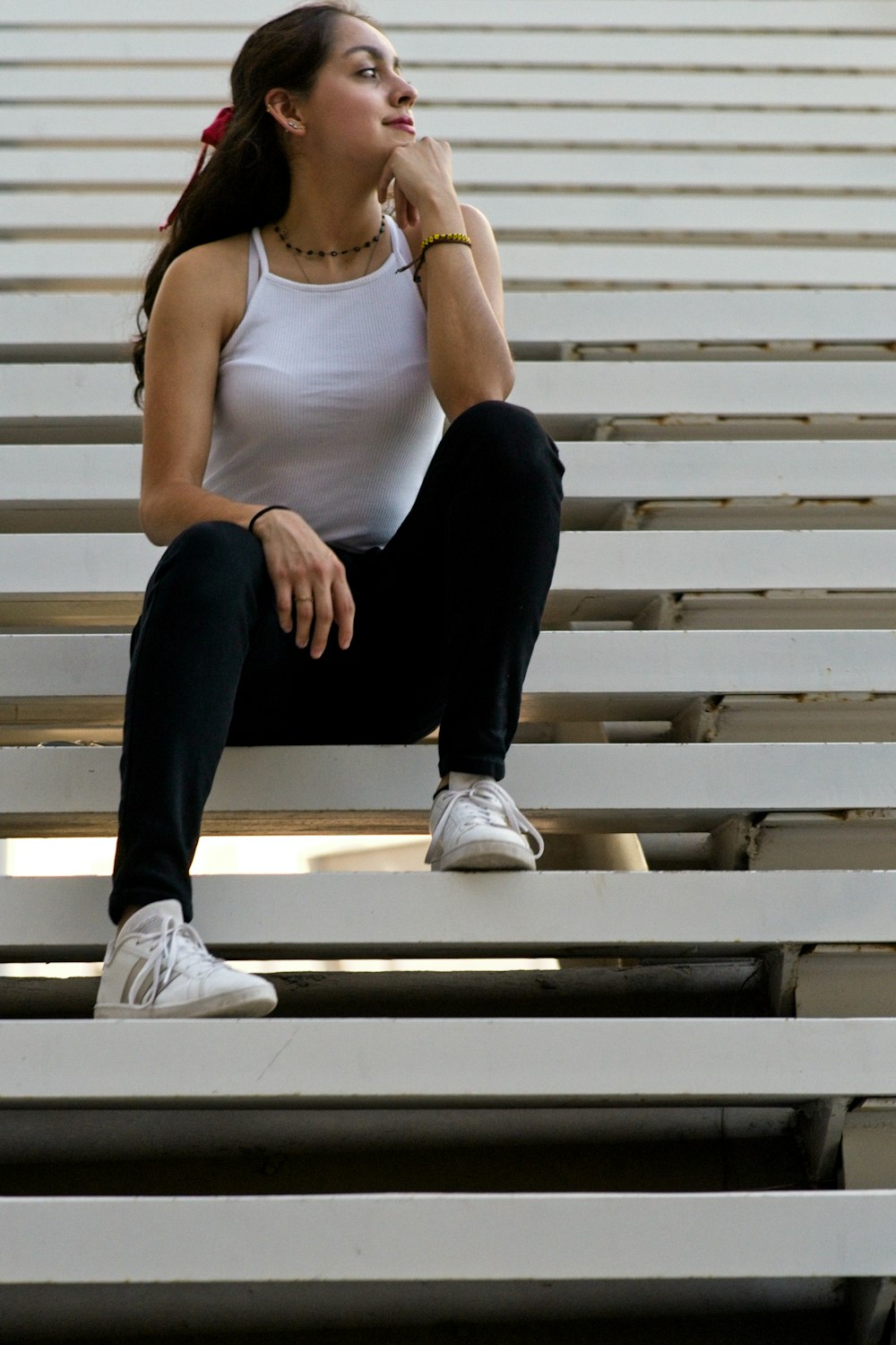 woman in white tank top and black pants sitting on white staircase