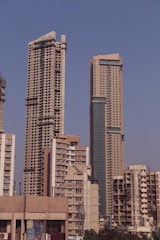 Tall skyscrapers dominate the city skyline, with construction evident on one of the high-rise buildings. The scene features a mix of modern architecture against a clear blue sky.