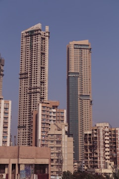 Tall skyscrapers dominate the city skyline, with construction evident on one of the high-rise buildings. The scene features a mix of modern architecture against a clear blue sky.