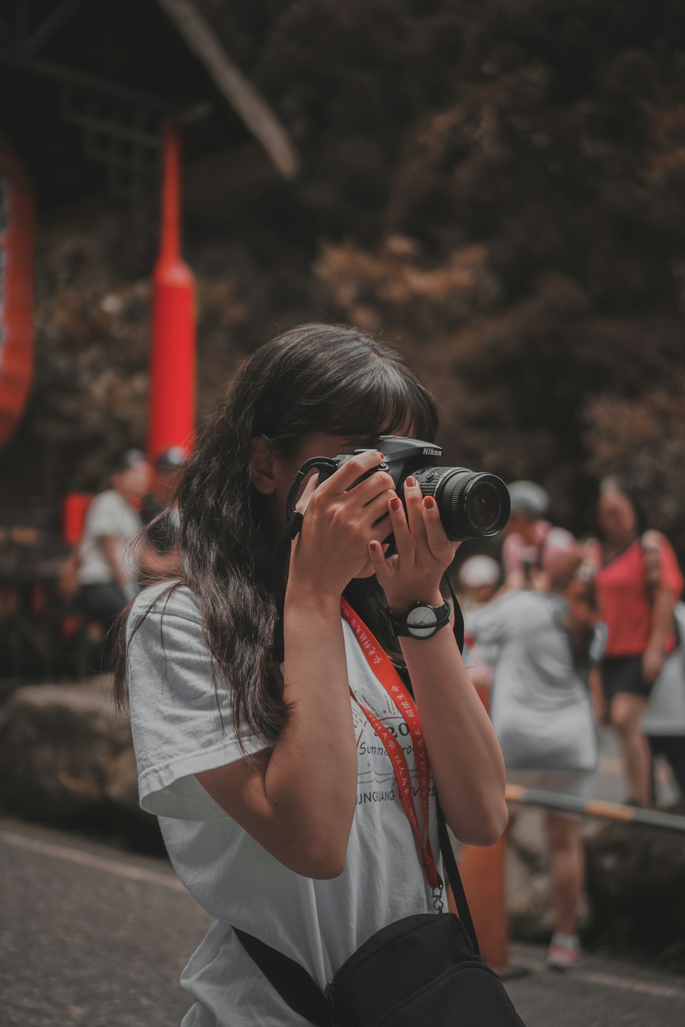 woman in white t-shirt holding black dslr camera