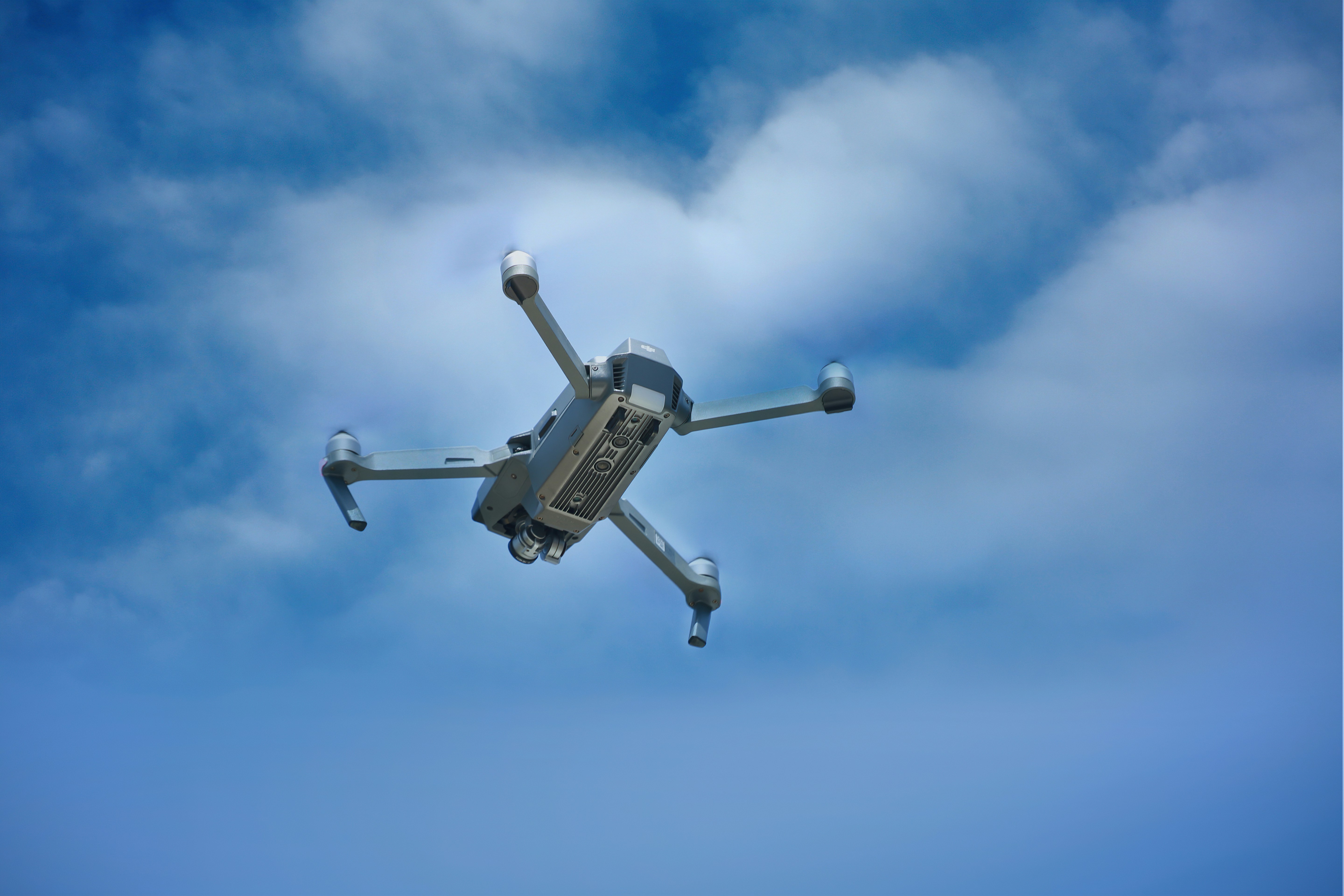 gray drone flying under blue sky during daytime