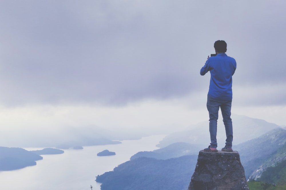 man in blue jacket standing on rock formation during daytime