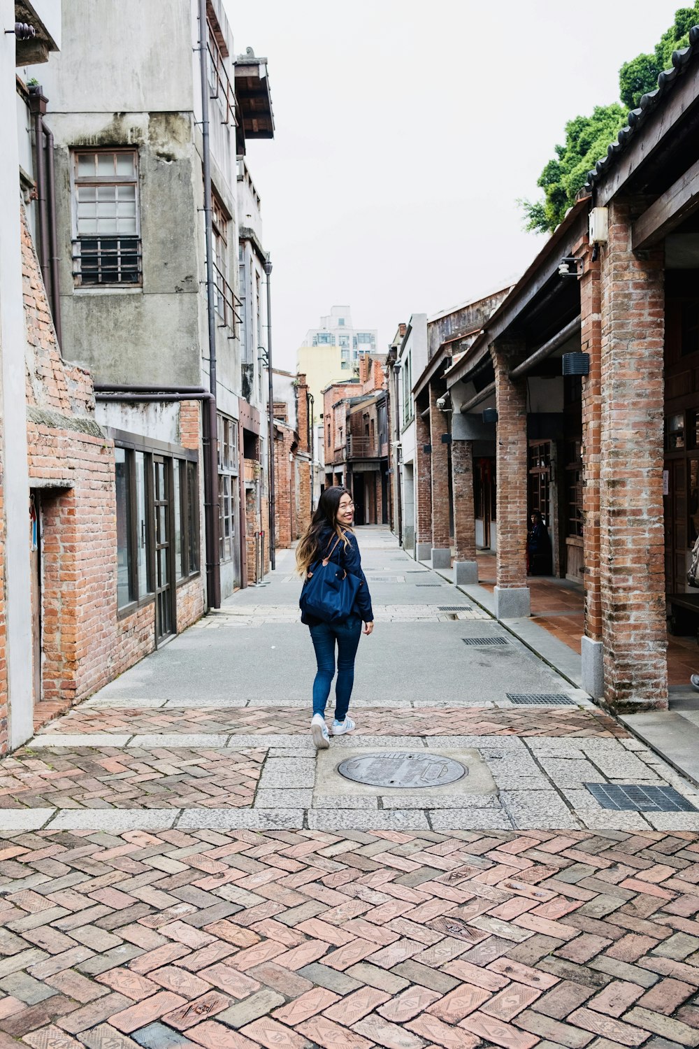 woman in blue jacket walking on sidewalk during daytime