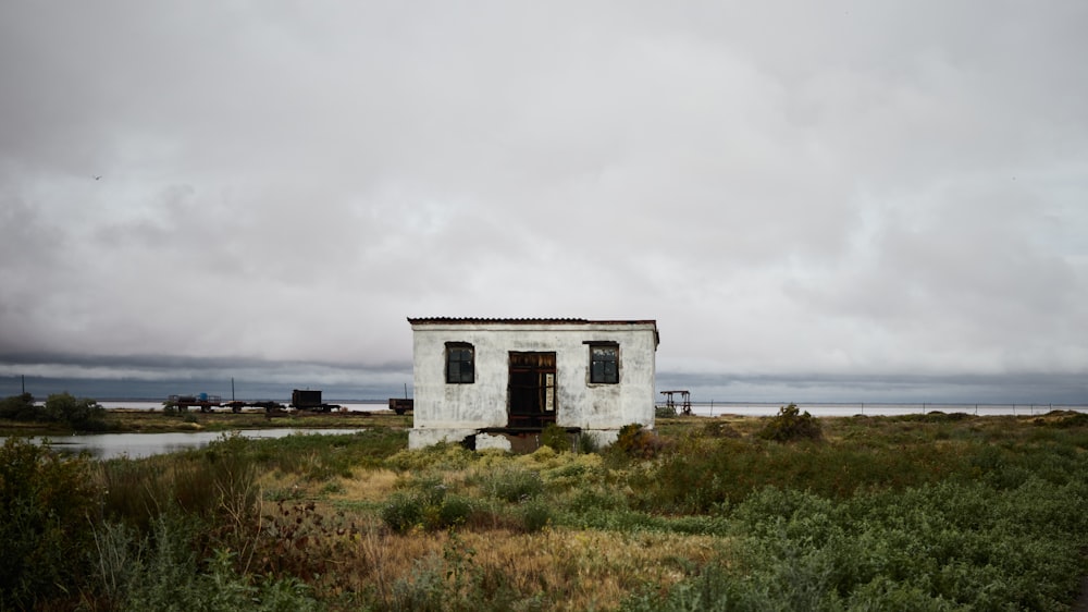 white concrete house near green grass field under white clouds during daytime