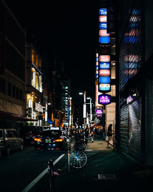 man in black jacket riding bicycle on road during night time in Sakae Japan