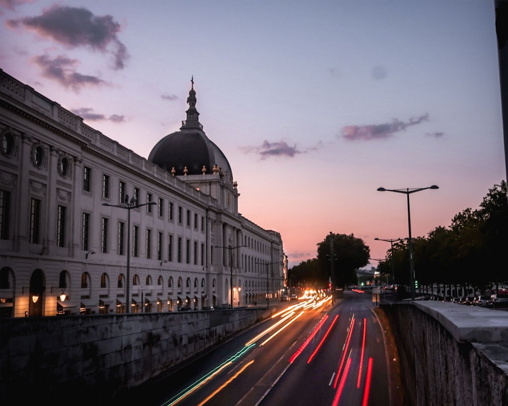 time lapse photography of cars on road near white concrete building during night time