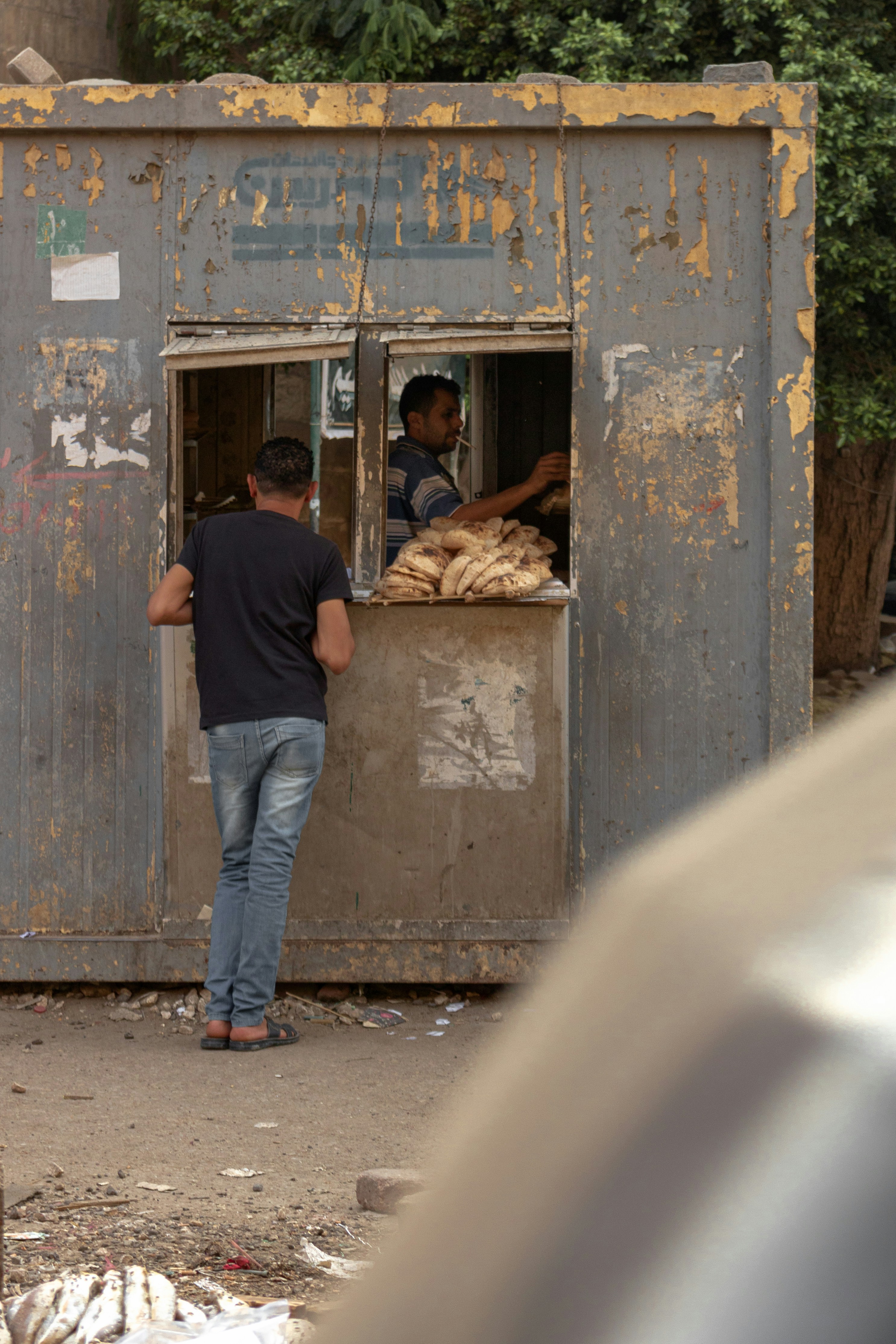 Mann in schwarzem T-Shirt und blauer Jeans tagsüber neben brauner Holztür