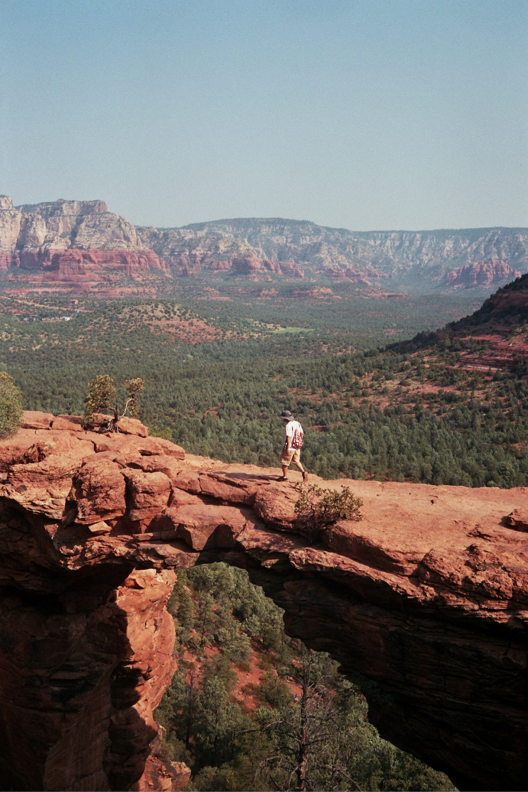 man in white shirt standing on brown rock formation during daytime