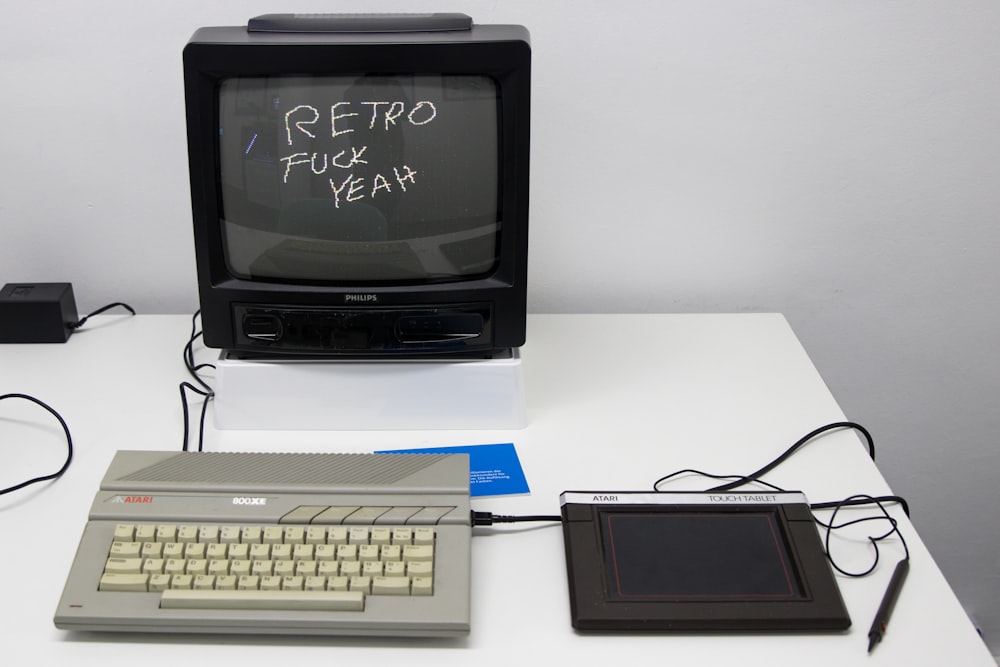 흰색 컴퓨터 키보드 옆에 있는 검은색 CRT TV