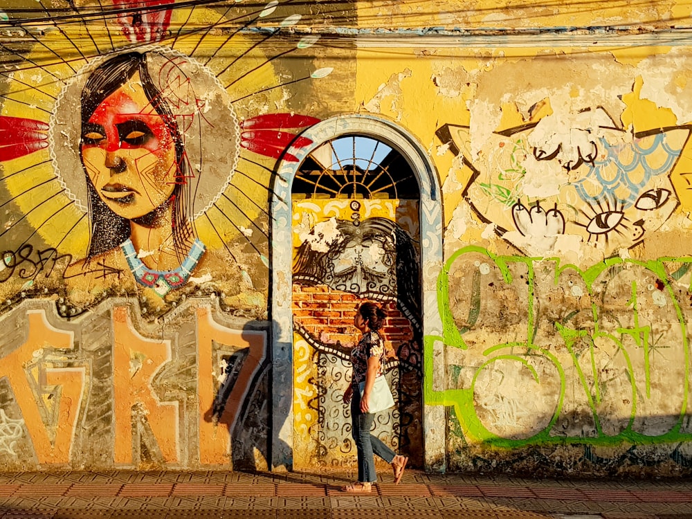 a person standing in front of a building with graffiti on it
