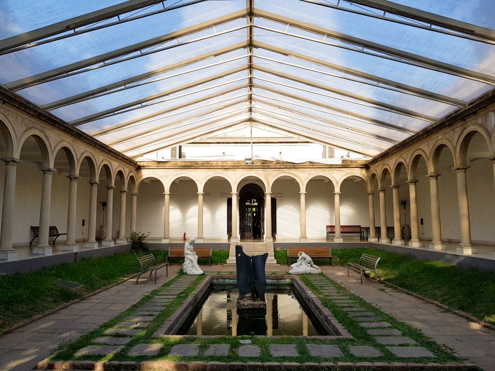 a building with a glass roof and a pond inside of it