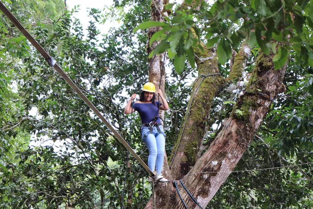 man in yellow hard hat climbing on tree during daytime