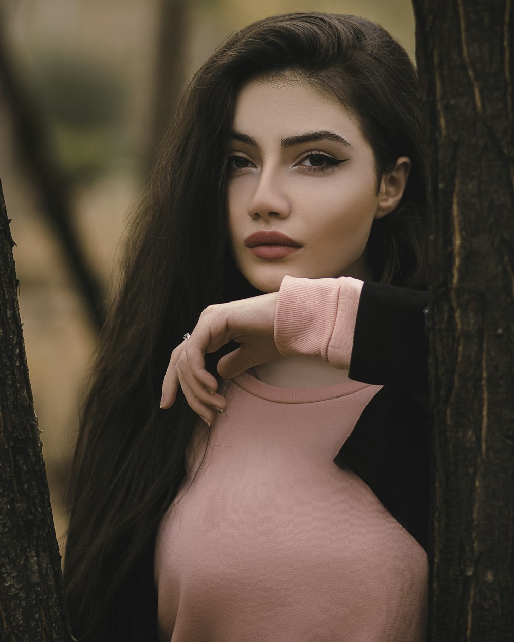 woman in black long sleeve shirt leaning on brown tree