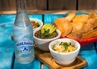 blue and white labeled bottle beside white ceramic bowl with food