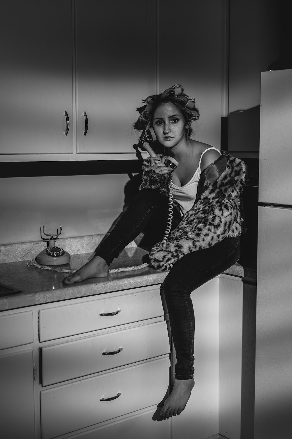 woman in black and white spaghetti strap top and black pants sitting on kitchen sink