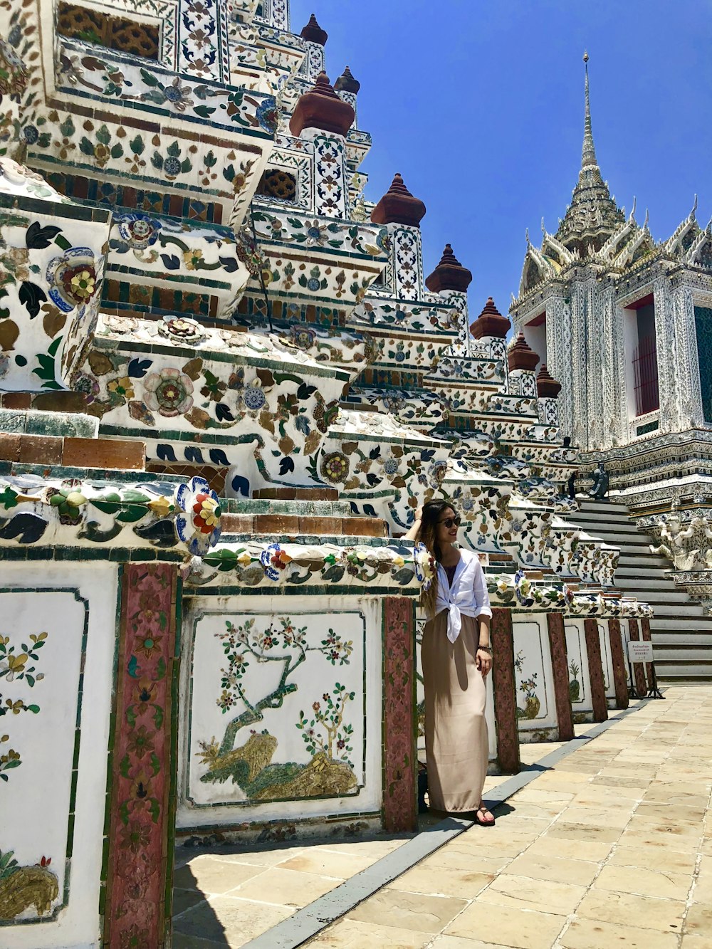 woman in white and blue dress standing in front of white and blue floral painted building