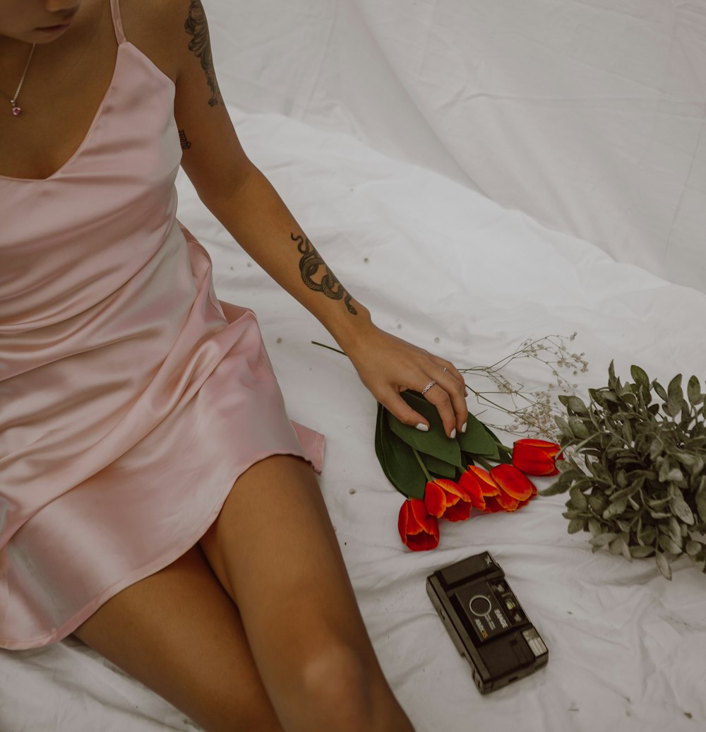 woman in pink spaghetti strap dress holding red rose